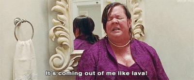 Picture of Melissa McCarthy in Bridesmaids saying "It's coming out of me like lava"